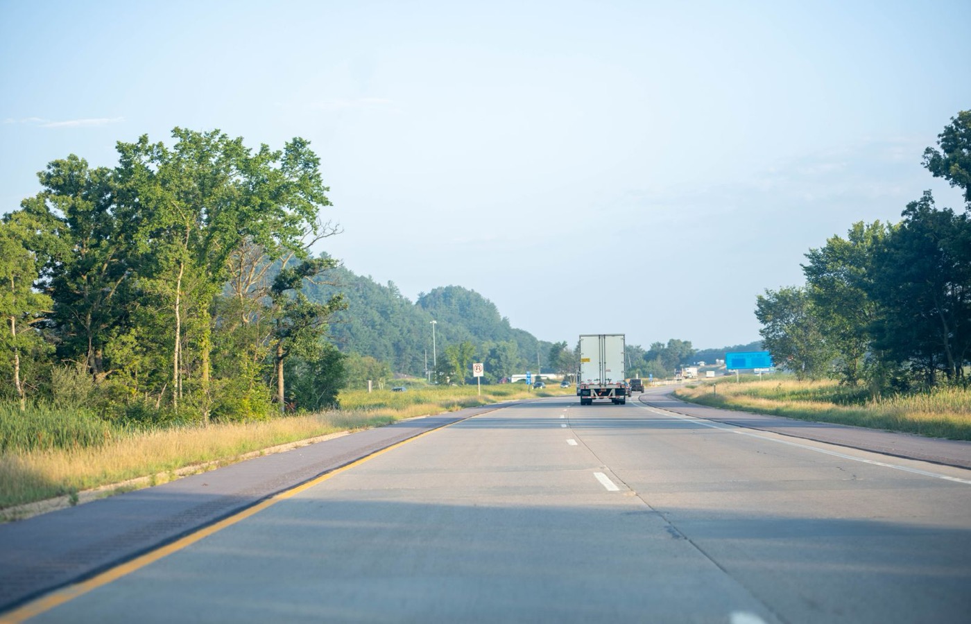 A Midwest highway with a trailer ahead of the camera on a hazy morning